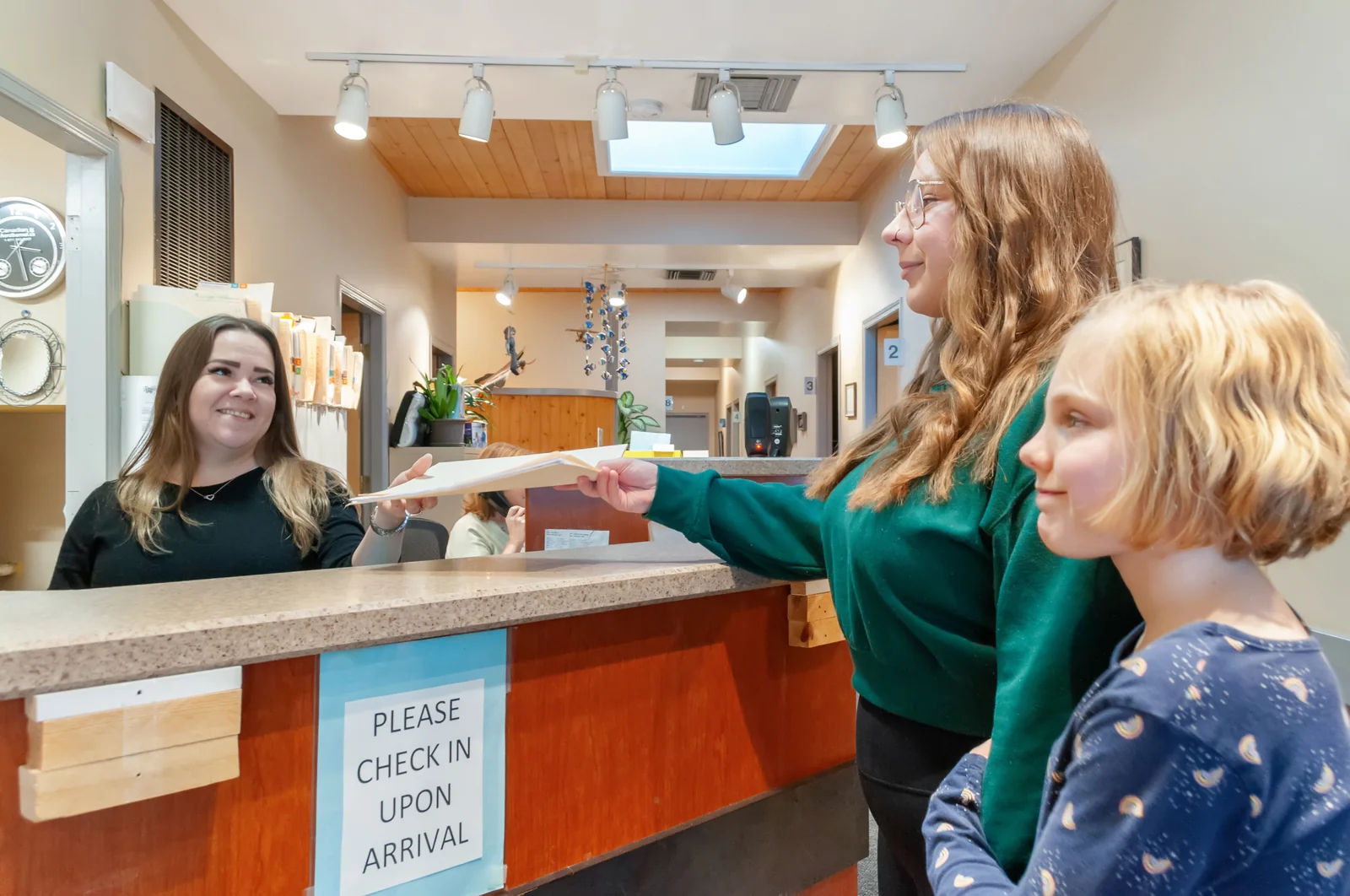 OCC receptionist warmly greeting a family at the front desk in Penticton